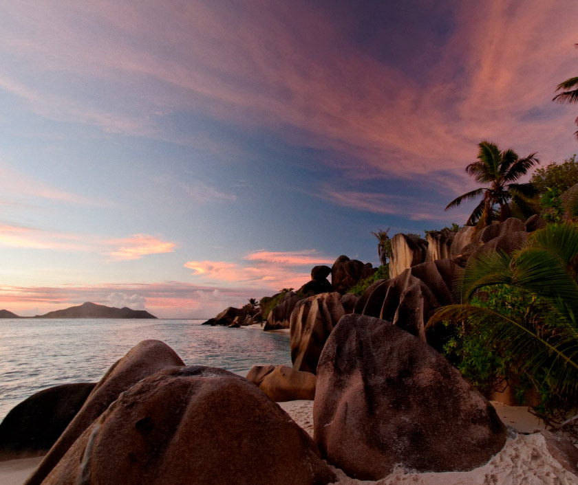 Beautiful landscape setting of Seychelles, with smooth rocks and trees, with a view of the ocean, Experience Seychelles with ExecuJet.