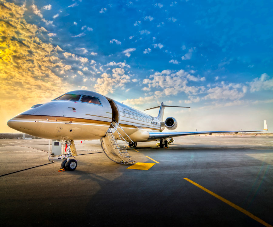 This image invites you into a moment at ExecuJet's Sabiha Gokcen ramp parking, where a private jet is gracefully positioned on the tarmac. Feel the sleek and smooth contours of the jet's body, and notice the open door, suggesting a welcome or perhaps a farewell. The surroundings are caressed by the gentle glow of a setting sun. Picture the sky, awash in soft hues of orange and pink, where clouds are painted in delicate strokes, their shapes illuminated by the fading daylight.The entire scene creates a harmony between the marvel of human engineering and the natural beauty of the day's end. There's a sense of elegance and tranquility in this picture, an intimate glimpse into the world of private aviation, where luxury and nature's grace intertwine.