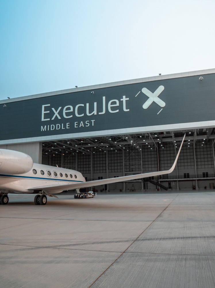 A gleaming private aircraft parked in front of ExecuJet Middle East's state-of-the-art hangar facility at Dubai Al Maktoum International Airport.