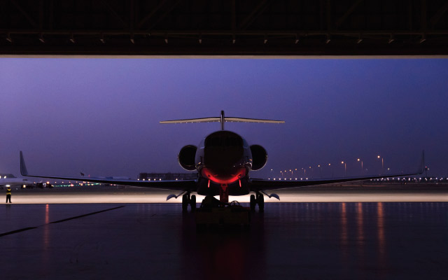Front view of aircraft parked inside the hangar with a stunning night sky backdrop.