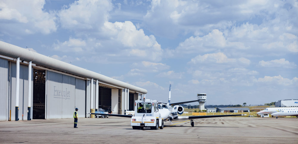 A view of Lanseria Apron showcasing hangar, aircraft on apron, and clear blue skies, exemplifying thriving aviation resilience.